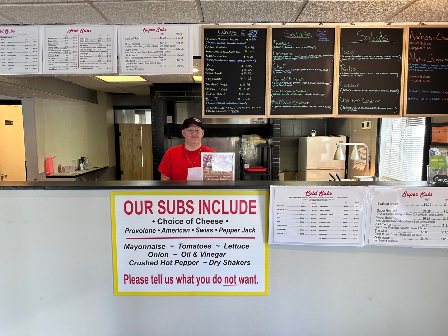 Counter, menu boards, and staff member inside Mike's Mr. Subs